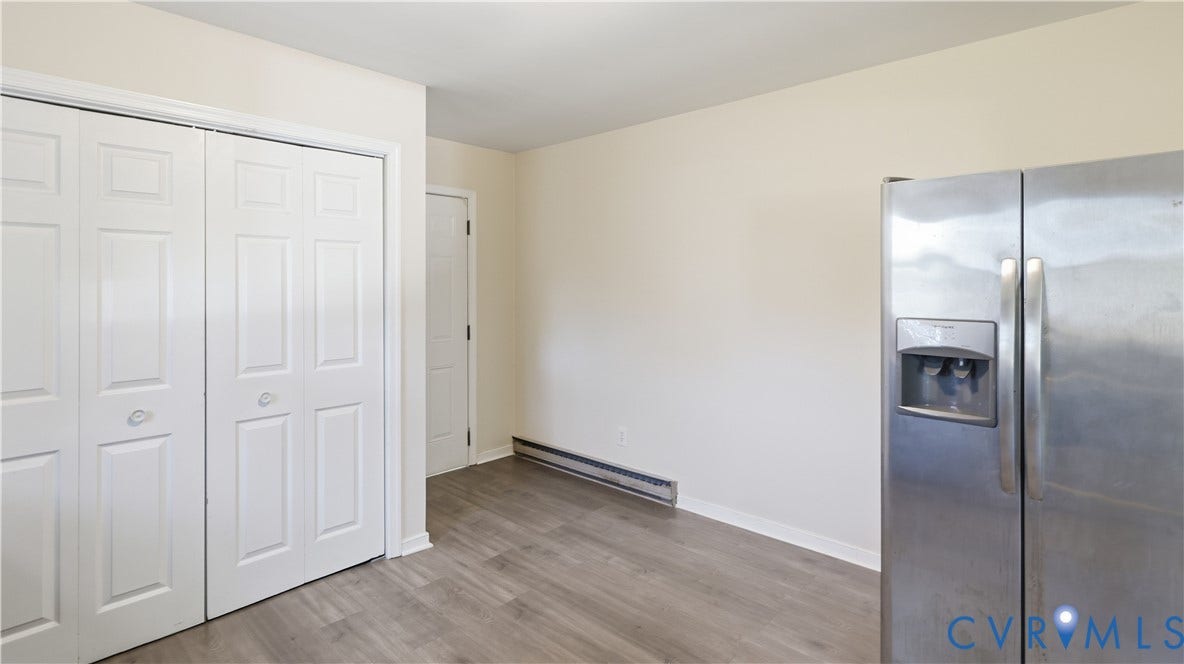 Wood-finish flooring, double-door closet with white paneling, and stainless steel side-by-side refrigerator