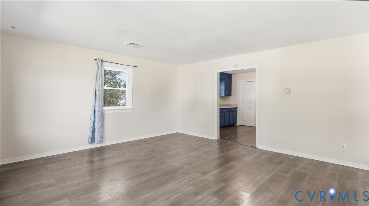 Neutral interior space featuring wood-finish flooring and a single-pane window