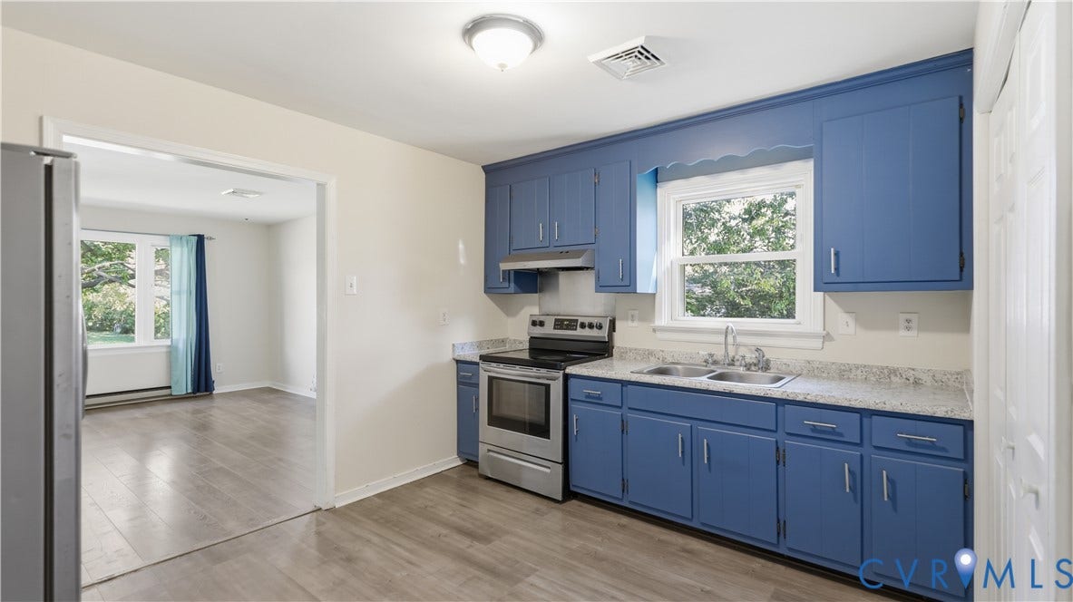 Kitchen featuring blue cabinetry, light-toned speckled countertops, stainless steel electric range, double-basin sink, and wood-finish flooring