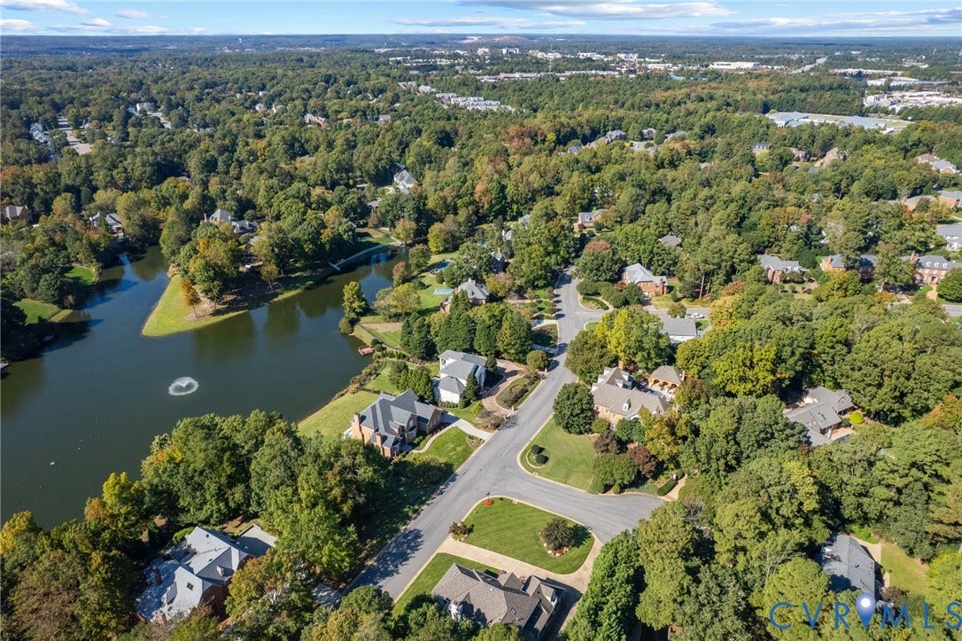 11433 Barrington Bridge Court, Henrico, VA 23233 Aerial perspective of a residential neighborhood featuring mature canopy trees, winding asphalt roads, and a large central lake with a fountain