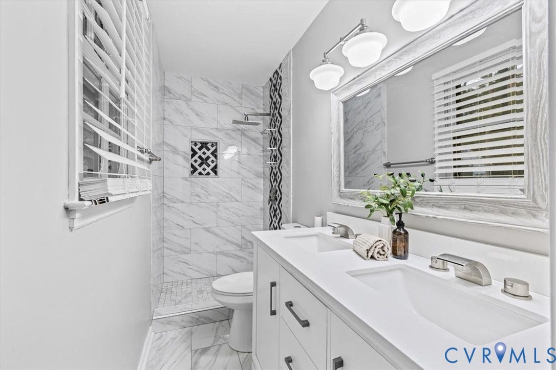 11518 Frederick Farms Circle, Midlothian, VA 23112 Dual-sink vanity with white countertop, stone-finish tile shower surround with geometric accent inlay, rainfall shower head, and wall-mounted vanity lighting