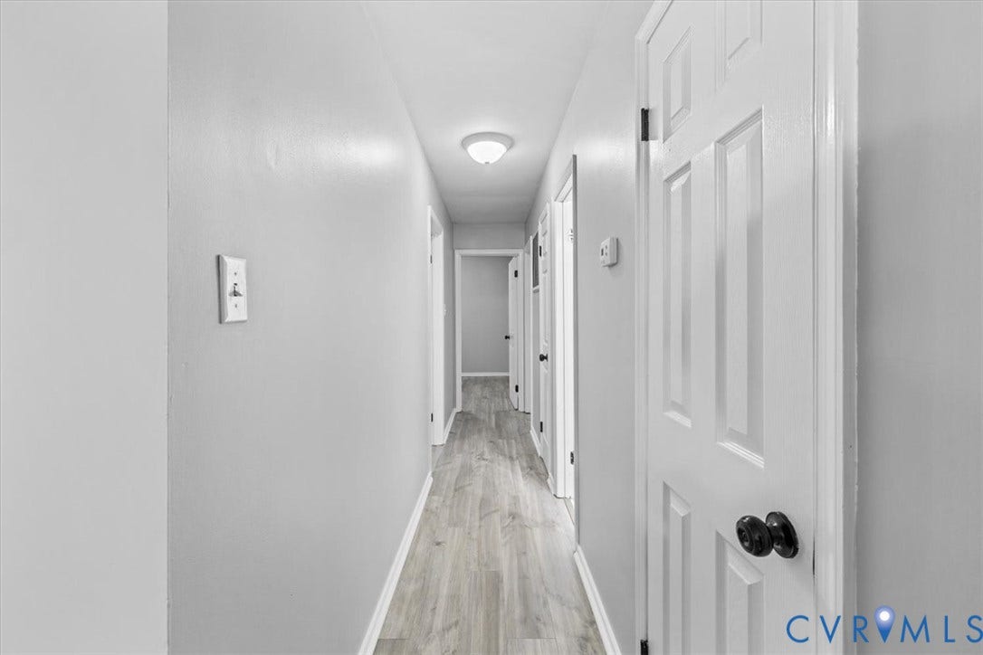 11518 Frederick Farms Circle, Midlothian, VA 23112 Hallway featuring wood-finish flooring, white six-panel doors, matte black hardware, and a flush-mount ceiling light fixture