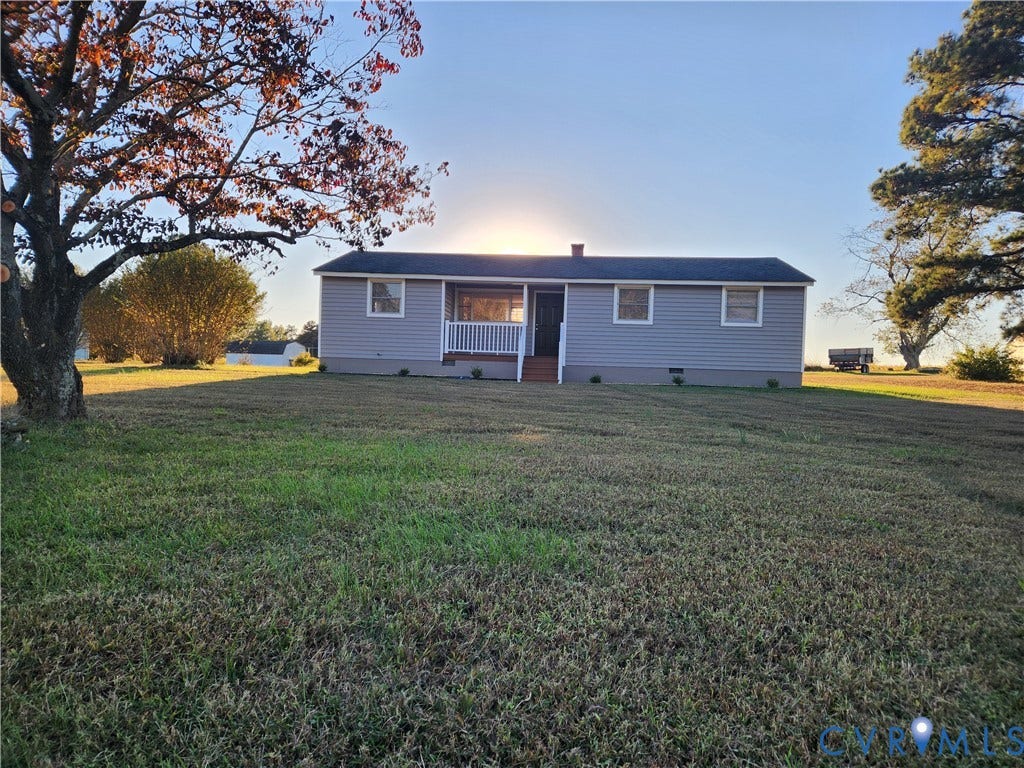 1209 Newtown Road, King & Queen, VA 23148 Single-story residence featuring light-toned horizontal siding, a covered front porch with white railing, and an expansive grass yard with mature trees