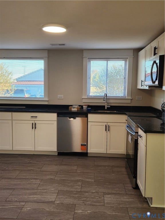 1209 Newtown Road, King & Queen, VA 23148 Kitchen featuring white Shaker-style cabinetry, dark stone-finish countertops, stainless steel appliances, and large-format tile flooring
