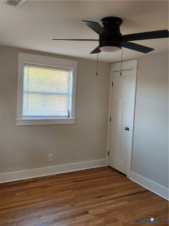 1209 Newtown Road, King & Queen, VA 23148 Interior space featuring wood-finish flooring, a multi-panel door, a window with decorative casing, and a black ceiling fan with an integrated light fixture