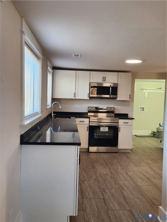 1209 Newtown Road, King & Queen, VA 23148 Kitchen featuring white cabinetry, dark stone countertops, stainless steel appliances, and wood-finish flooring