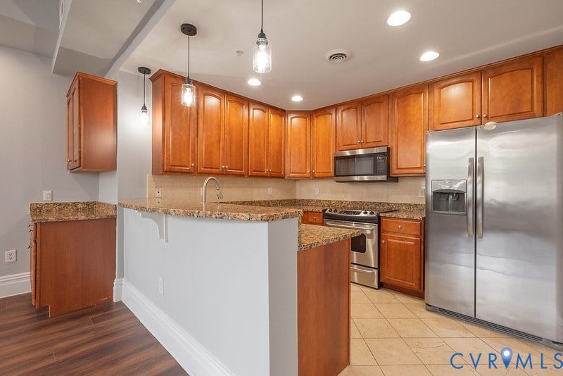 6 N 6th Street, #U3C, Downtown, Richmond, VA 23219 Kitchen featuring wood cabinetry, stone countertops, stainless steel appliances, pendant lighting, and tiled flooring