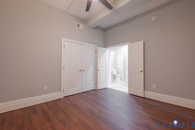 6 N 6th Street, #U3C, Downtown, Richmond, VA 23219 High ceilings featuring a dark-finish ceiling fan, wood-finish flooring, and white double-door closet cabinetry