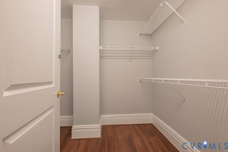 6 N 6th Street, #U3C, Downtown, Richmond, VA 23219 Walk-in closet featuring wood-finish flooring, white paneled door with brass-tone hardware, and tiered wire shelving
