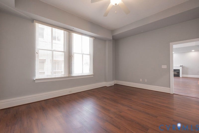 6 N 6th Street, #U3C, Downtown, Richmond, VA 23219 Room featuring wood-finish flooring, recessed tray ceiling with an integrated ceiling fan, and large windows with horizontal blinds