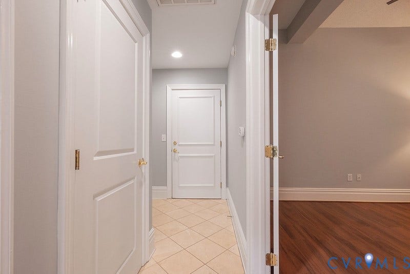 6 N 6th Street, #U3C, Downtown, Richmond, VA 23219 Entryway featuring neutral-toned tile flooring, recessed lighting, and multi-panel interior doors with brass hardware, complemented by wood-finish flooring in the adjacent room