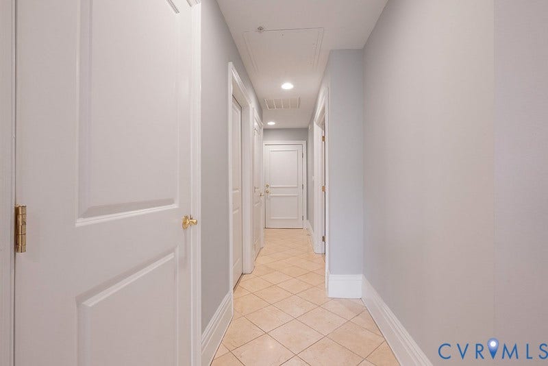 6 N 6th Street, #U3C, Downtown, Richmond, VA 23219 Hallway featuring light-toned diagonal tile flooring, smooth neutral-toned walls, and multiple solid-core interior doors with metallic hardware