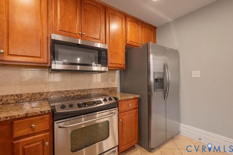 6 N 6th Street, #U3C, Downtown, Richmond, VA 23219 Kitchen featuring wood cabinetry, stone countertops, stone tile backsplash, stainless steel appliances, and tile flooring