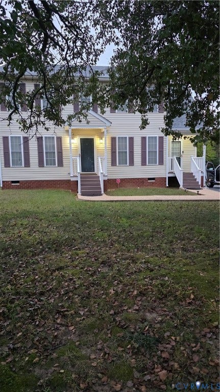 Two-story exterior featuring light-toned horizontal siding, brick foundation masonry, and decorative window shutters, accented by dual entryways with covered stoops