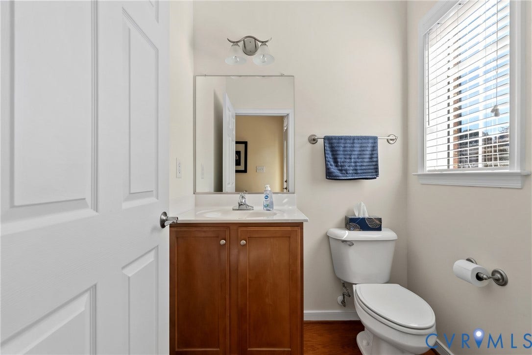 4914 Terrace Arbor Circle, Midlothian, VA 23112 Wood-finish cabinetry, white countertop with integrated sink, polished metal hardware, wall-mounted mirror with dual-light fixture, and wood-finish flooring