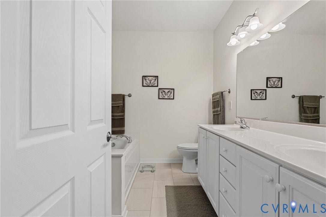 4914 Terrace Arbor Circle, Midlothian, VA 23112 Dual-sink vanity with white cabinetry, solid-surface countertop, full-width wall mirror, four-bulb overhead vanity lighting, and ceramic tile flooring