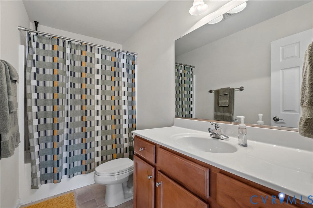 4914 Terrace Arbor Circle, Midlothian, VA 23112 Bathroom featuring a full-width vanity mirror, wood-finish cabinetry, a white countertop with an integrated basin, single-handle chrome faucet, and a tub-shower combination