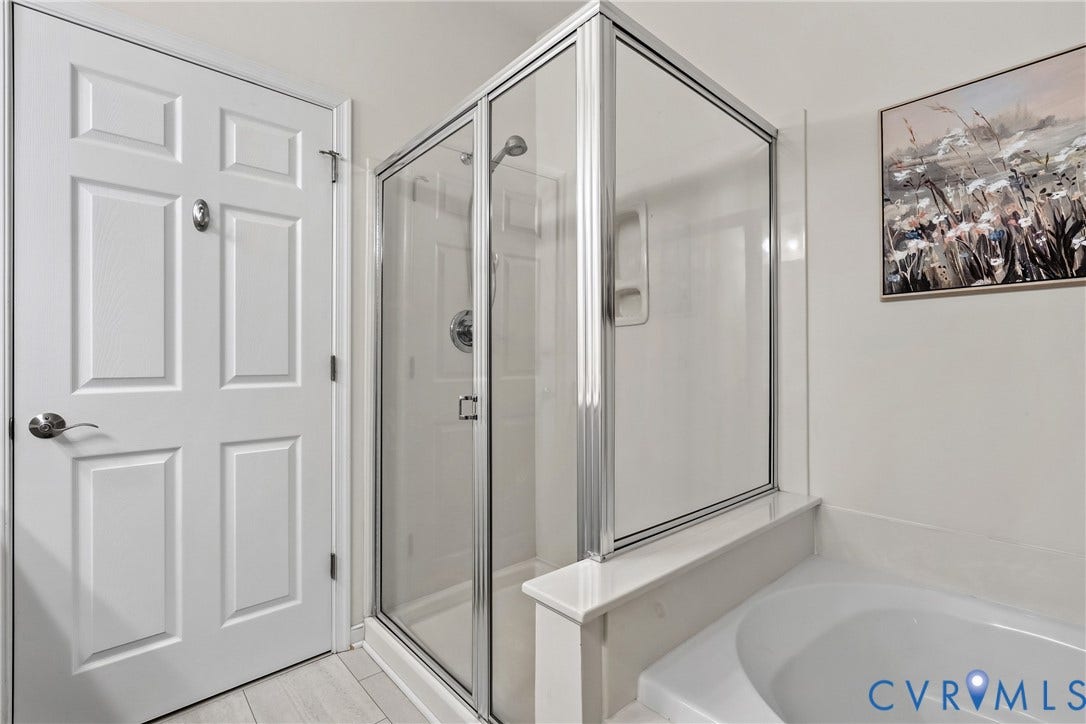 4914 Terrace Arbor Circle, Midlothian, VA 23112 Glass-enclosed shower with chrome fixtures and integrated shelving, paired with a deep soaking tub and a six-panel solid core door