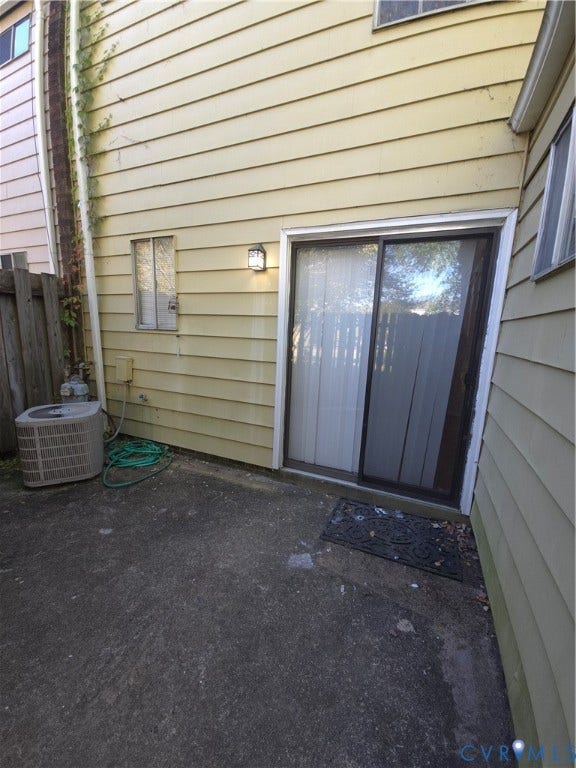 413 Adamson Street, Henrico, VA 23075 Exterior patio area featuring concrete hardscaping, horizontal siding, and a sliding glass door with external wall-mounted lighting
