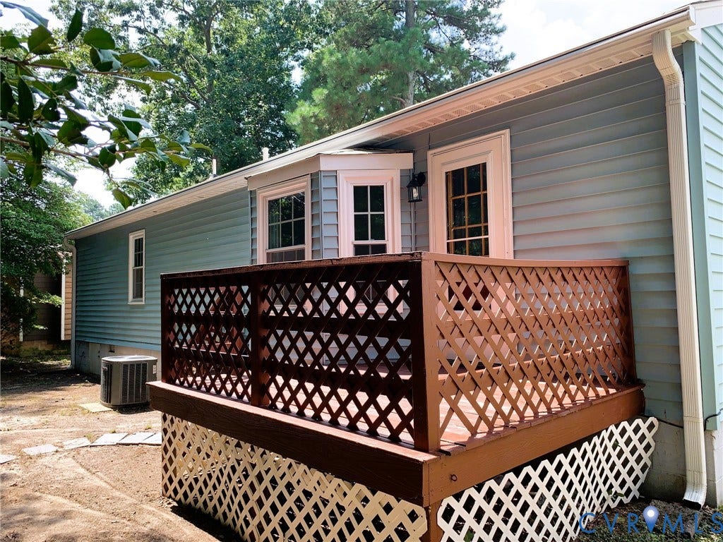 8905 Hawkbill Road, Chesterfield, VA 23237 Raised wood deck featuring lattice railing, bay window, light blue horizontal siding, and external light fixture