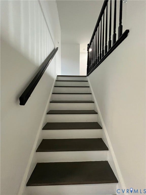 39 Rock Garden Lane, Henrico, VA 23228 Staircase featuring dark-toned treads, crisp white risers, and a high-contrast black handrail with matching balusters