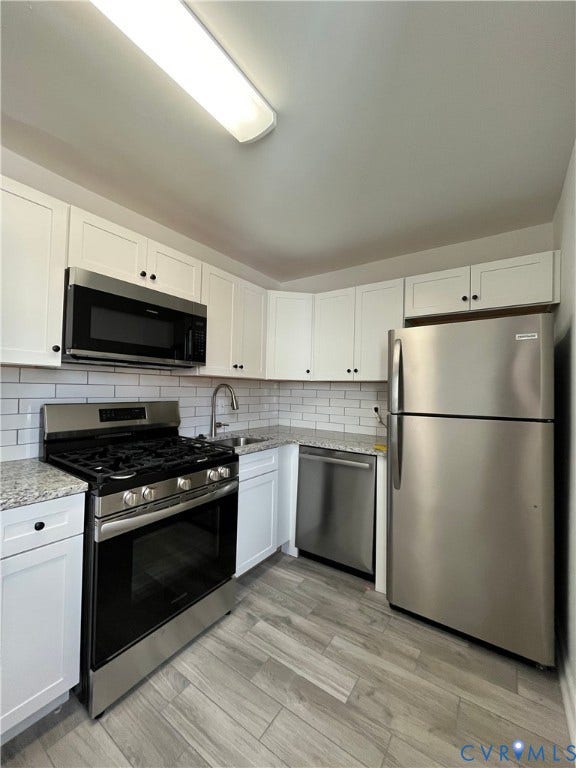39 Rock Garden Lane, Henrico, VA 23228 Kitchen featuring white cabinetry, stone-surface countertops, subway tile backsplash, stainless steel appliances, and wood-finish flooring