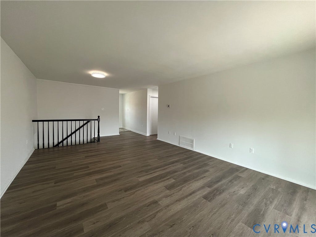 39 Rock Garden Lane, Henrico, VA 23228 Open-concept interior featuring wood-finish flooring, neutral walls, and a black metal staircase railing