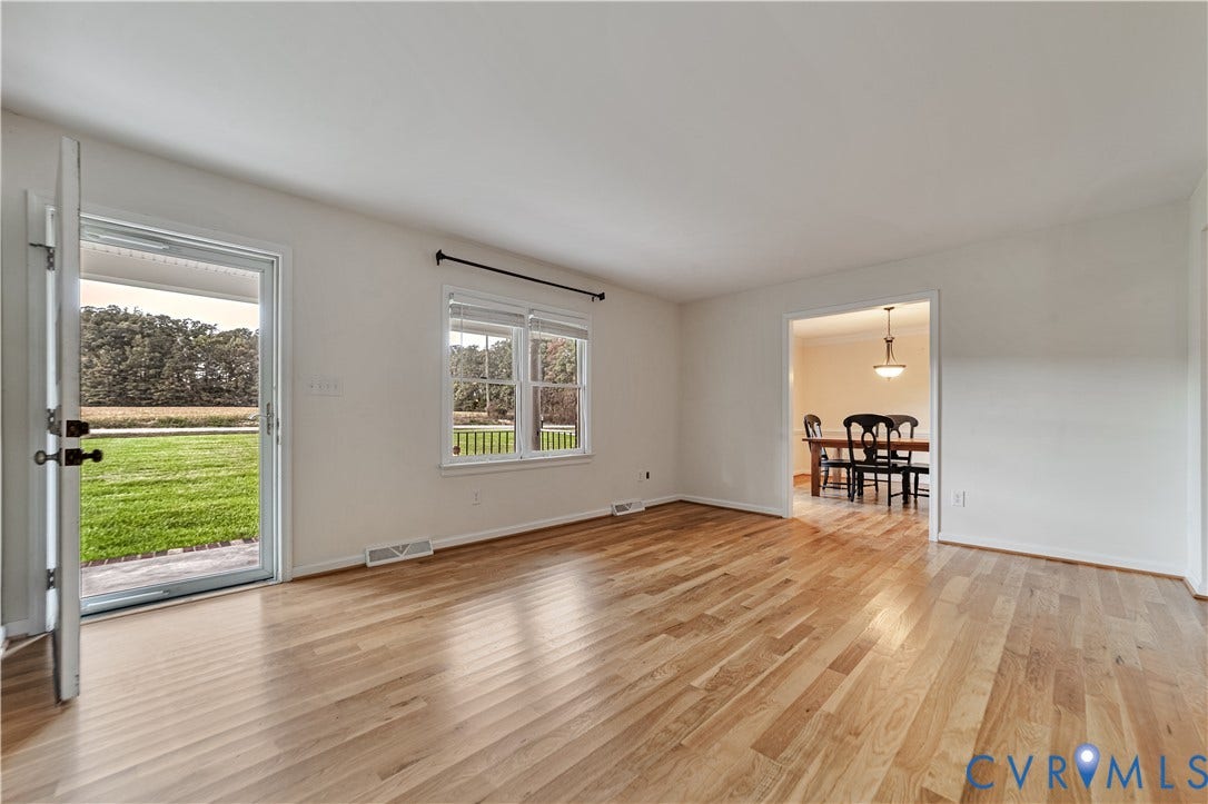 Light-filled room featuring wood-finish flooring, a glass-paneled exterior door, and double-hung windows