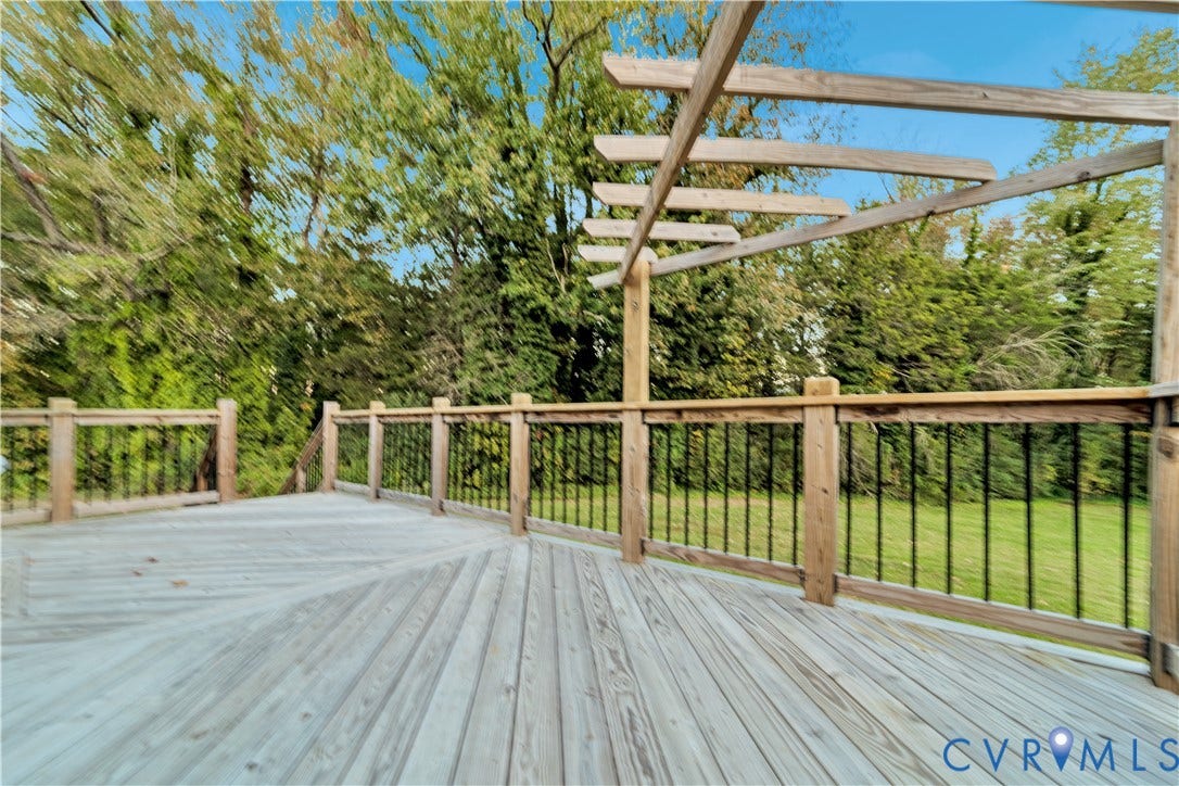 Elevated wood deck featuring a wooden pergola, wood railings, and metal balusters