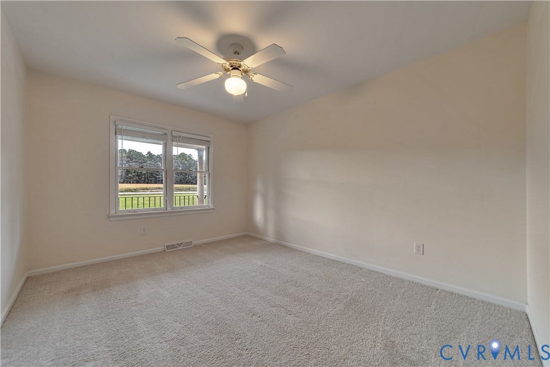Neutral-toned room featuring neutral wall-to-wall carpeting, a multi-blade ceiling fan with an integrated light fixture, and double-pane windows