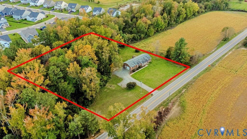 Expansive parcel featuring mature trees, manicured lawn, and a paved driveway