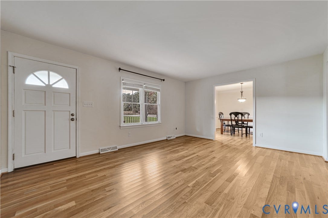 Wood-finish flooring, white paneled entry door with semi-circular window, and double-pane window with hardware