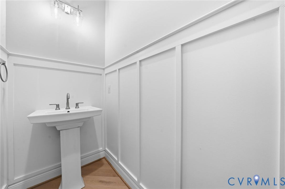 18132 Dogwood Trail Way, Rockville, VA 23146 White board-and-batten wall detailing, pedestal sink with chrome faucet, multi-light vanity fixture, and wood-finish flooring
