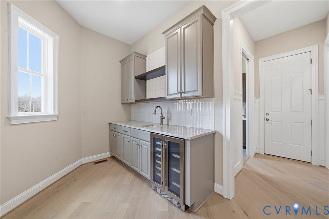 18132 Dogwood Trail Way, Rockville, VA 23146 Custom cabinetry with built-in beverage refrigerator, stone-surface countertop, sink with gooseneck faucet, white vertical tile backsplash, and wood-finish flooring