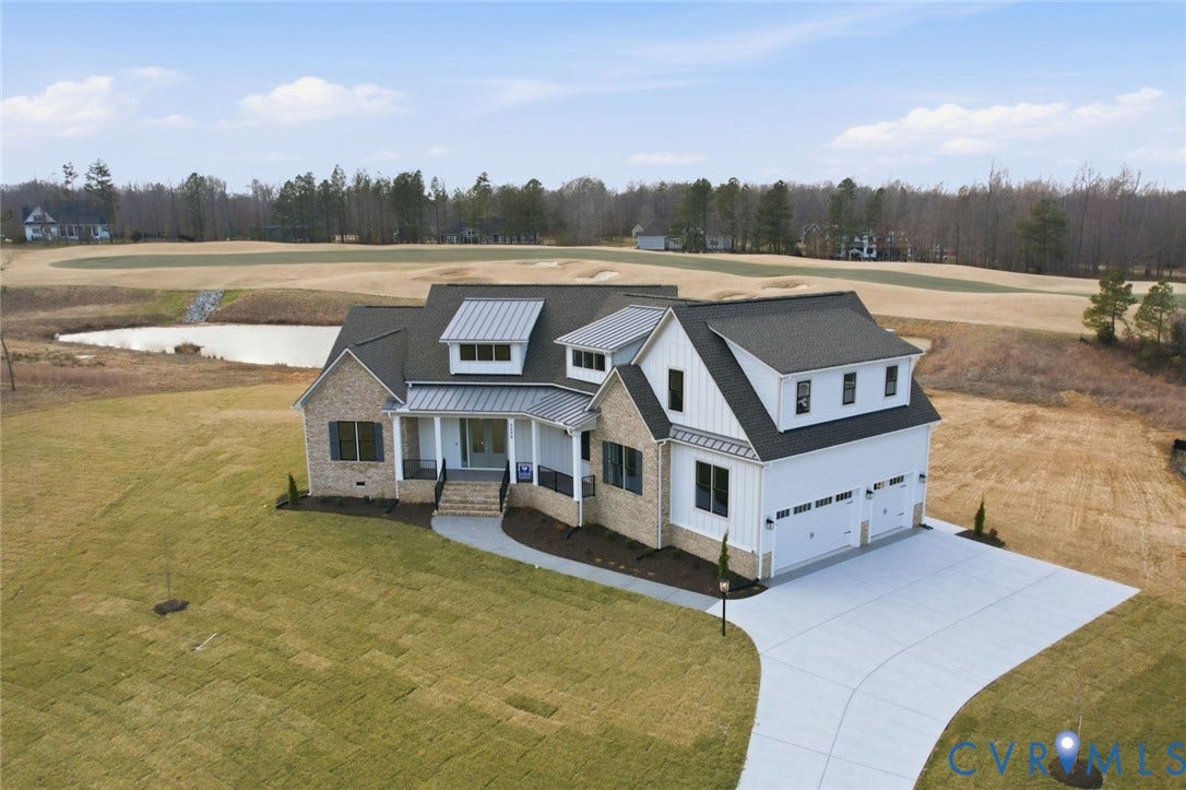 18132 Dogwood Trail Way, Rockville, VA 23146 Two-story residence featuring a brick and vertical siding exterior, metal roof accents, covered front porch with iron railing, and attached two-car garage
