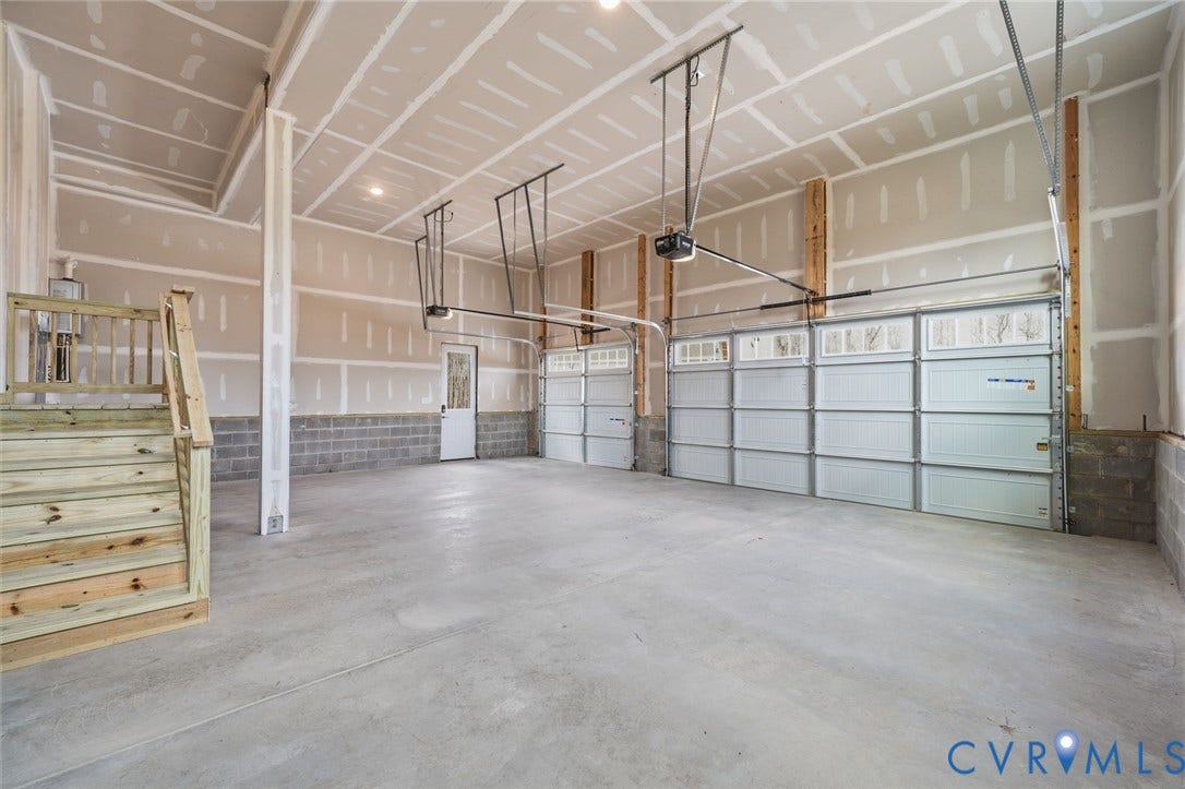 18132 Dogwood Trail Way, Rockville, VA 23146 Spacious multi-car garage featuring a smooth concrete floor, high ceilings, automatic roll-up doors, and wooden staircase access