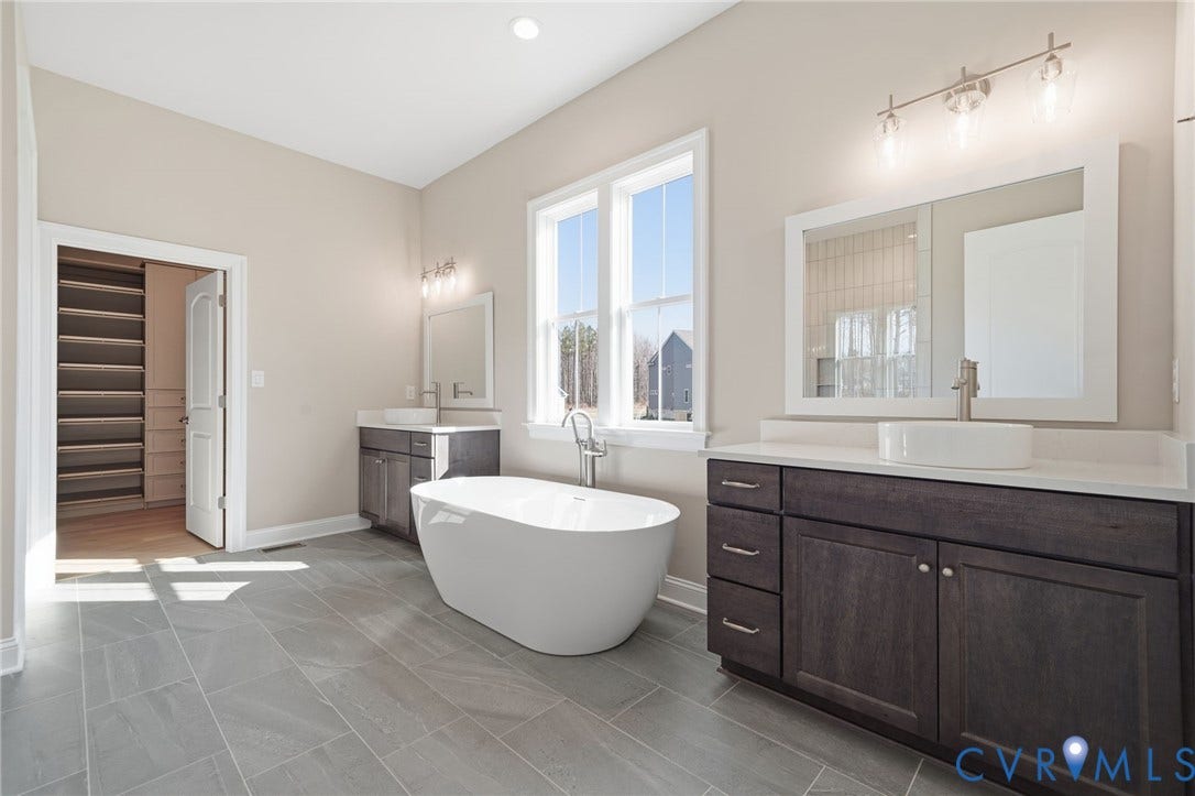 18132 Dogwood Trail Way, Rockville, VA 23146 Freestanding soaking tub, dual vanities with white vessel sinks, quartz countertops, dark-finish cabinetry, and large-format tile flooring