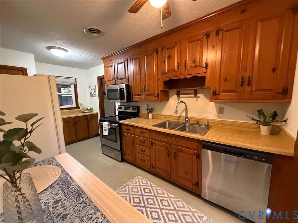 9012 Shawonodasee Road, Courthouse, Chesterfield, VA 23832 Kitchen featuring wood cabinetry, stainless steel appliances, dual-basin sink with arched faucet, and laminate countertops