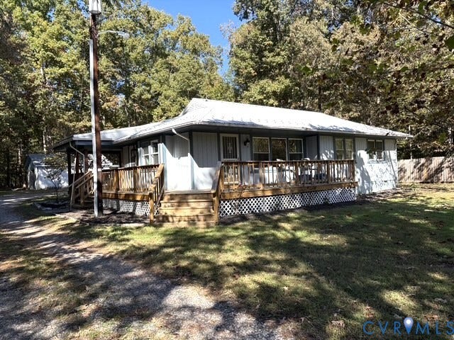 9012 Shawonodasee Road, Courthouse, Chesterfield, VA 23832 Exterior featuring light-toned vertical siding, a metal roof, and an expansive wood deck with lattice skirting, situated on a wooded lot