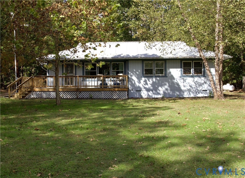 9012 Shawonodasee Road, Courthouse, Chesterfield, VA 23832 Single-story exterior featuring light-toned vertical siding, a metal roof, an expansive wood deck, and decorative lattice skirting