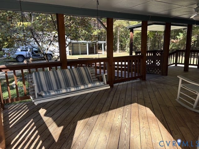 9012 Shawonodasee Road, Courthouse, Chesterfield, VA 23832 Covered wood deck featuring a built-in porch swing, wood railing, lattice accents, and a ceiling fan