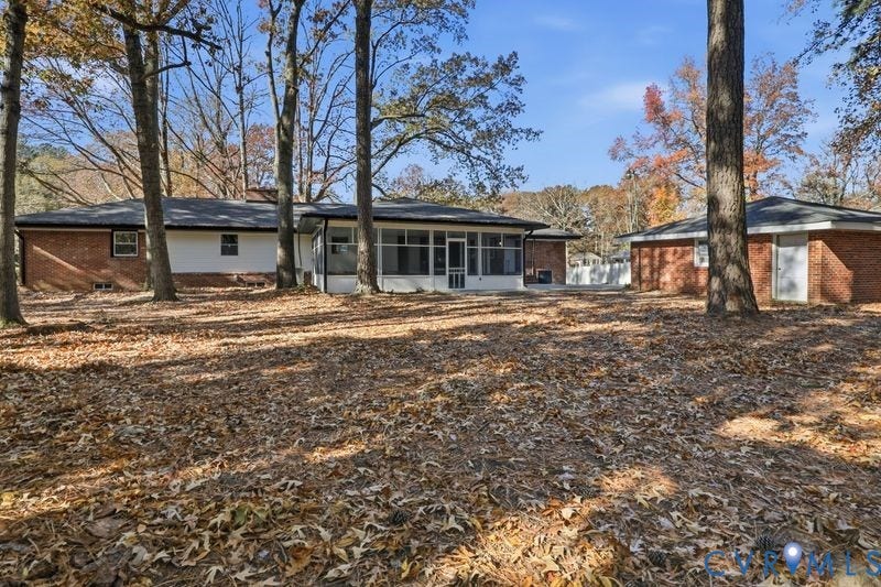 Expansive backyard featuring mature trees, red brick exterior, a screened-in porch, and a detached structure