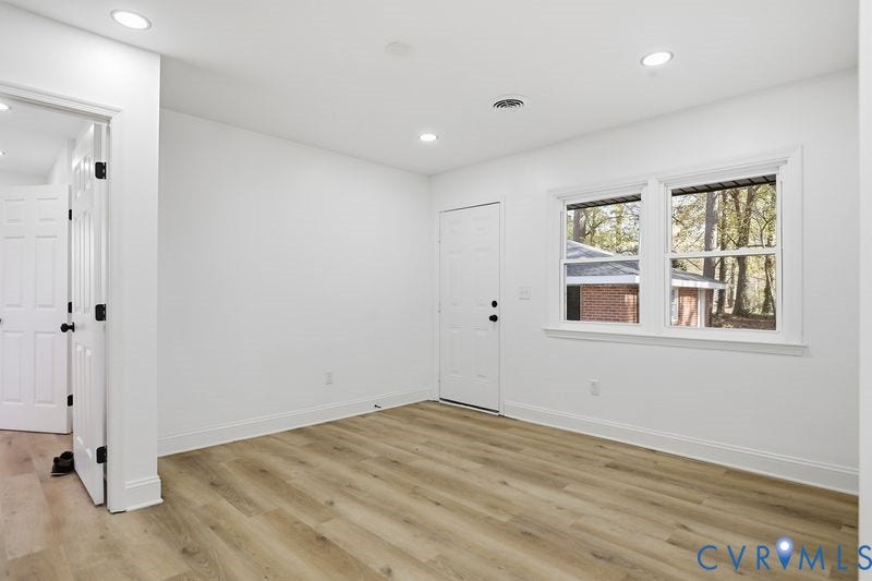 Interior room featuring wood-finish flooring, recessed lighting, double-pane windows, and a solid-panel door