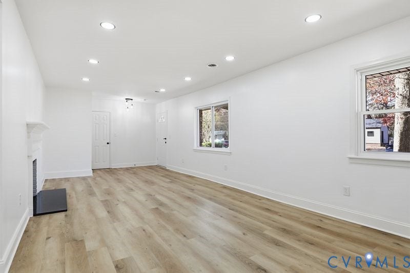 Interior space featuring wood-finish flooring, recessed lighting, double-hung windows, and a fireplace with a mantel