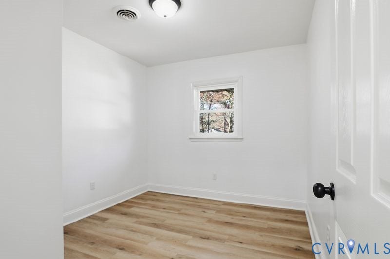 Interior space featuring wood-finish flooring, white walls, and a single-pane window