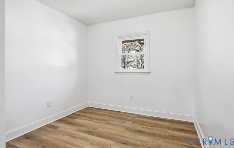 Neutral-toned walls paired with wood-finish flooring and a white-frame window