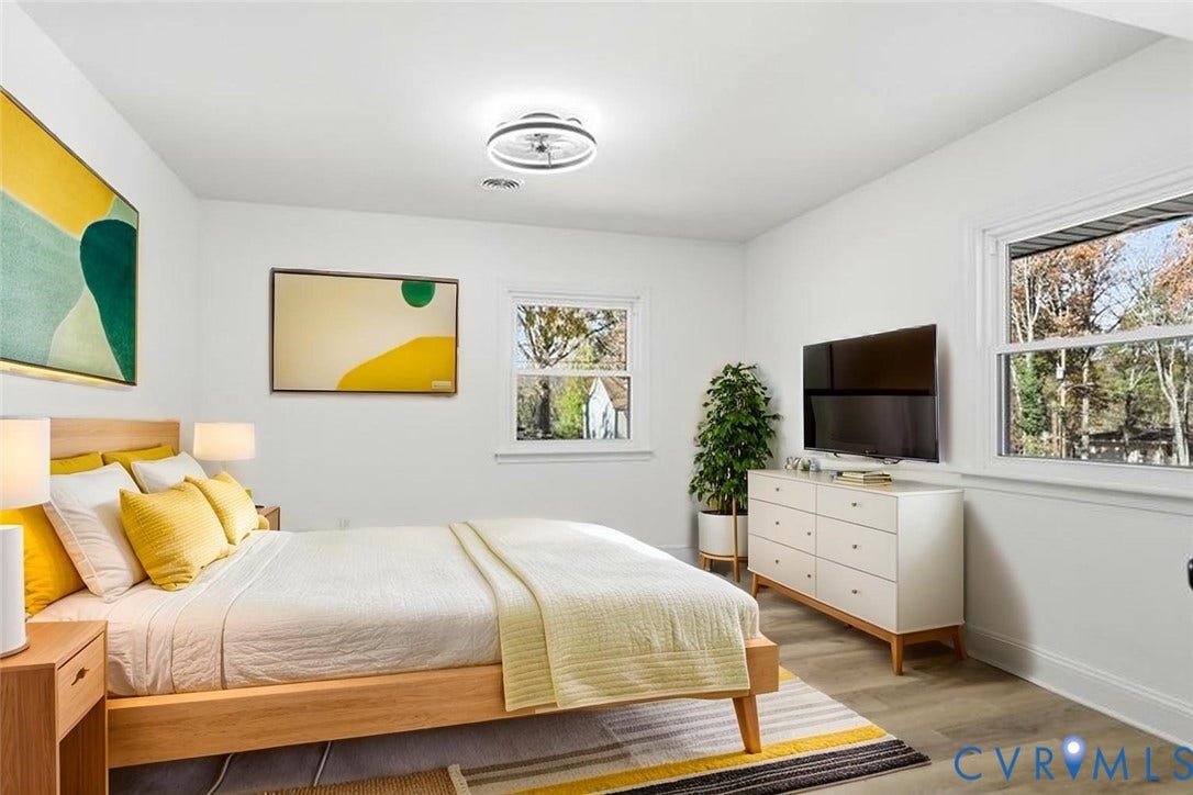 Neutral-toned interior featuring wood-finish flooring, dual windows with exterior trim, and a modern ceiling-mounted light fixture