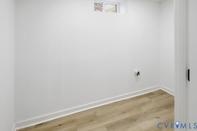 Room interior featuring wood-finish flooring, crisp white walls, and a recessed window