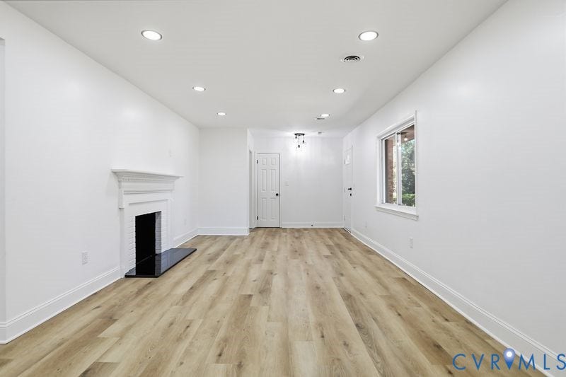 Wood-finish flooring, recessed lighting, fireplace with a decorative mantel and hearth, and neutral wall paint