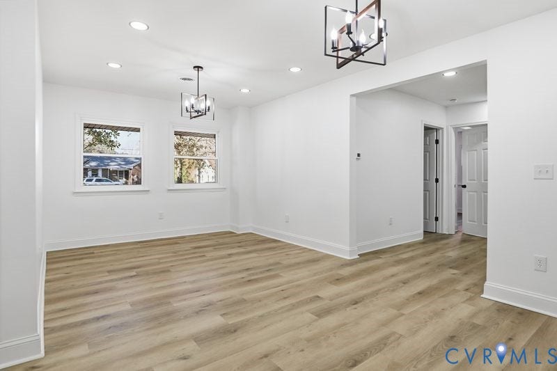 Interior space featuring wood-finish flooring, recessed lighting, dual iron-frame chandeliers, and double-pane windows